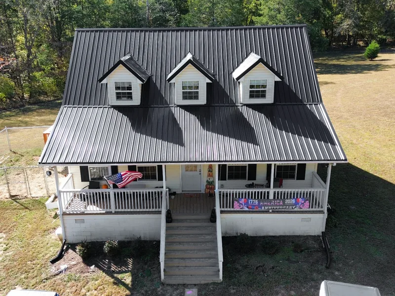 Same home after, with black Ag panel metal over the dormers and porch