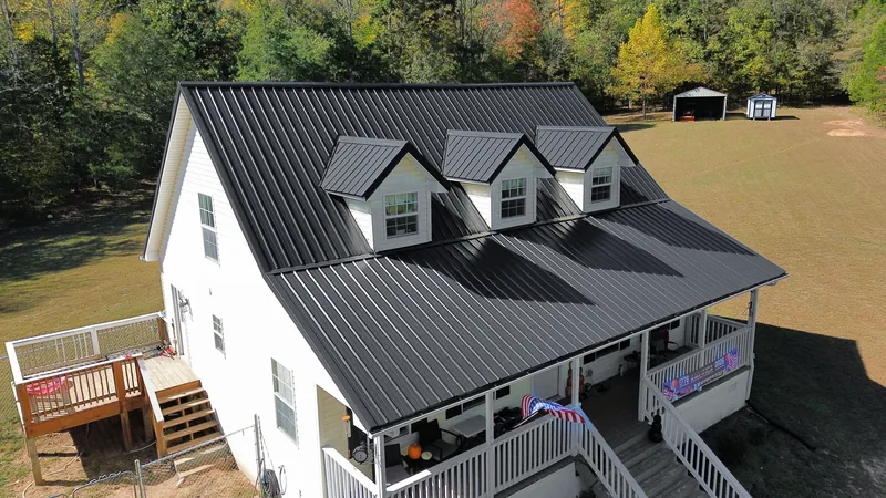 Drone view from the deck side: black Ag panel over the main roof, all three front dormers and the porch