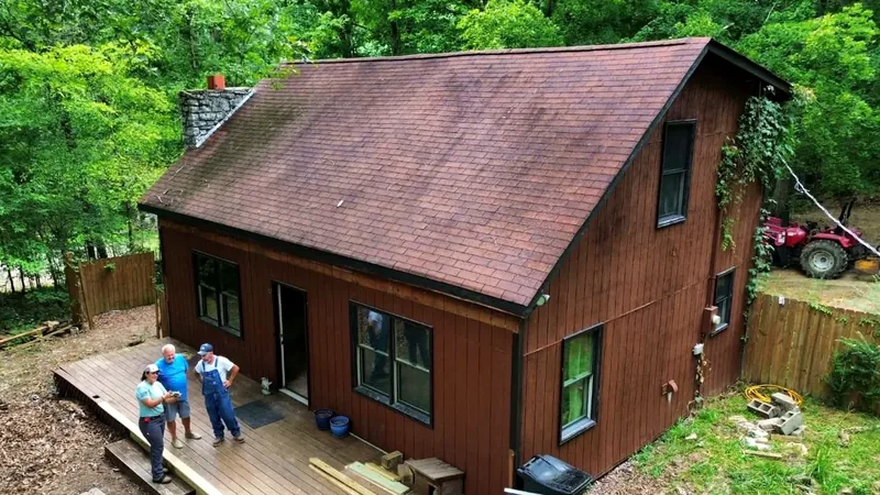 Cabin before, with a worn brown shingle roof