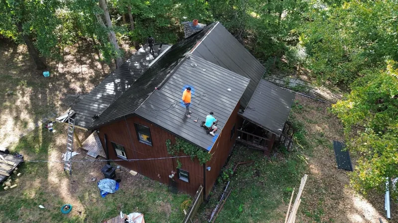 TRS crew installing a matte black Ag panel roof, seen from the drone